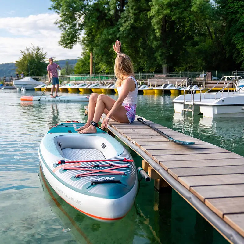 a photo of a lady sitting on a dock ready to get into the Cascade Hybrid SUP 