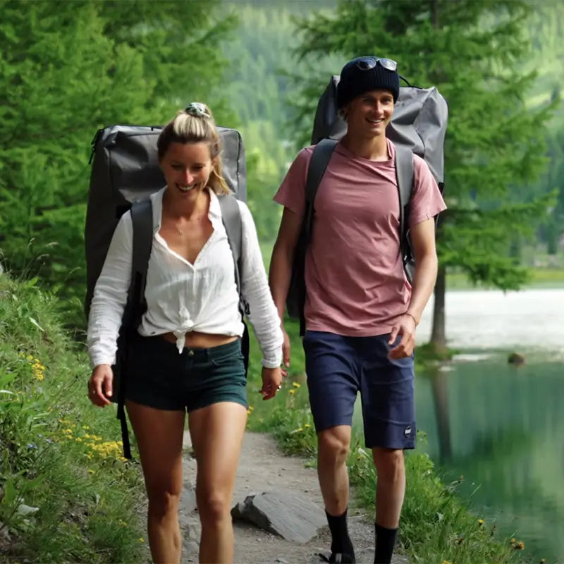 A couple walking to their launch point carrying the Cascade Hybrid in its backpack